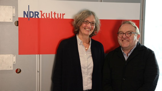 Eine Frau und ein Mann stehen lächelnd nebeneinander. Hinter ihnen ist ein großer rot-weißer Banner mit der Aufschrift NDR Kultur. © Franziska Dieckmann / NDR Foto: Franziska Dieckmann / NDR