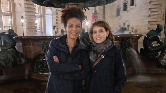 Jackie Thomae und Barbara Bleisch stehen bei Nacht vor einem Brunnen in Hamburg. © NDR Foto: Alexander Solloch