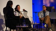 Joachim Dicks, Ulla Lenze und Daniel Schreiber sitzen auf Stühlen auf einer Bühne und lachen sich an. © Literaturhaus Hildesheim 