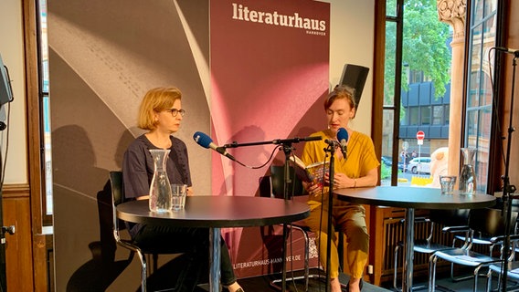 Claudia Christophersen und Nora Bossong sitzen an Tischen auf einer Bühne. © NDR Foto: Alexander Solloch