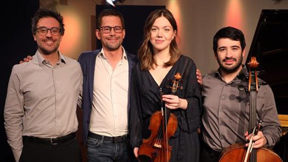 Das Trio Orelon mit NDR Kultur Moderator Philipp Cavert. Von links nach rechts: Pianist Marco Sanna, Philipp Cavert, Violinistin Judith Stapf, Cellist Arnau Rovira i Bascompte blicken freundlich in die Kamera. © NDR Foto: Franziska Diekmann