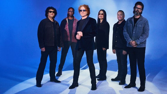 Die Band Simply Red posiert vor einem blauen Hintergrund. © Live Nation 