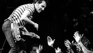 Bruce Springsteen spielt Gitarre auf einer Bühne - Hände ragen aus dem Zuschauerraum hervor. Transparenzhinweis: Das Foto stammt von einem Konzert in New Jersey, 1981. © picture alliance 