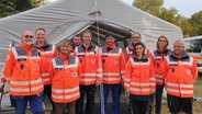 Mitglieder der Medical Task Force 13 Grevesmühlen posieren vor einem Zelt. © NDR Foto: Wiebke Heiden