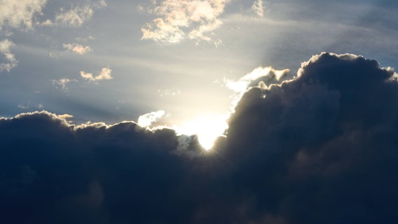 Sonne bricht hinter einer dicken Wolke hervor. Man sieht schon die kräftigen Strahlen. © IMAGO / Bihlmayerfotografie 