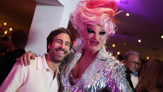 Sänger Max Giesinger und Drag Queen Olivia Jones stehen in der Pause während der Deutschlandpremiere des Broadway-Musicals "& Julia" im Stage Operettenhaus. © Marcus Brandt/dpa +++ dpa-Bildfunk +++ 