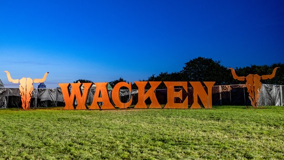 Das Festival-Logo gefertigt aus großen Metallbuchstaben, steht auf einer Wiese. © picture alliance/dpa Foto: Axel Heimken