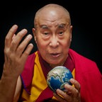 Der Dalai Lama hält einen kleinen Globus in der Hand und blickt in die Kamera. © picture alliance/dpa/X Verleih AG | - 