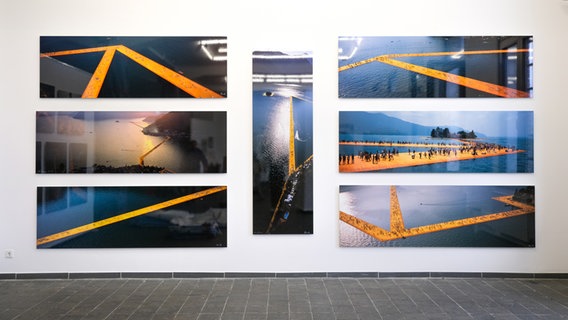 Fotos an einer Wand zeigen Stege in einem See, auf denen Menschen laufen. © Kunsthalle Lüneburg 