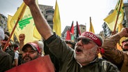 Menschen schwenken in Beirut Hisbollah-Fahnen, während einer Solidaritätsdemonstration mit den Palästinensern. © dpa Foto: Marwan Naamani