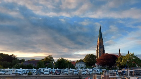 Panoramaaufnahme des Stadthafens von Schleswig mit dem Dom und vielen Wohnmobilen am Ufer. © NDR Foto: Sabine Thieme