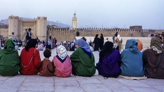 Frauen sitzen auf einer Mauer in Fez vor Bab Boujeloud © imago Foto: Danita Delimont