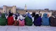 Frauen sitzen auf einer Mauer in Fez vor Bab Boujeloud © imago Foto: Danita Delimont