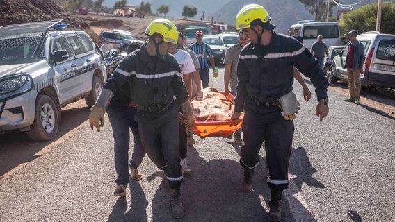 Mitglieder der Rettungsteams tragen die Leiche eines Erdbebenopfers im Dorf Wargan in der Nähe von Marrakesch.  © AP Foto: Musab Al-Shami