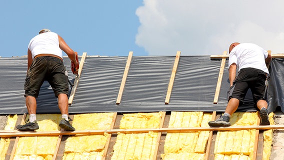 Zwei Dachdecker bringen Dämmschichten auf einem Dach an. © Horst Schmidt - Fotolia.com 