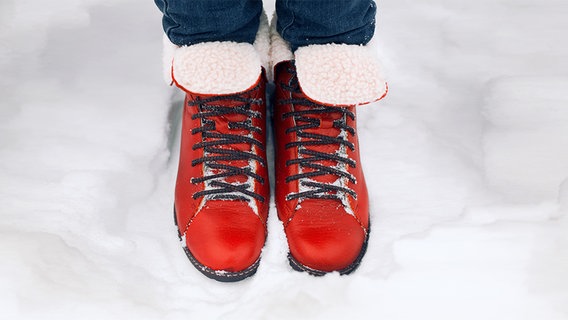 Füsse in rote Stiefel stehen im Schnee © fotolia Foto: solominviktor