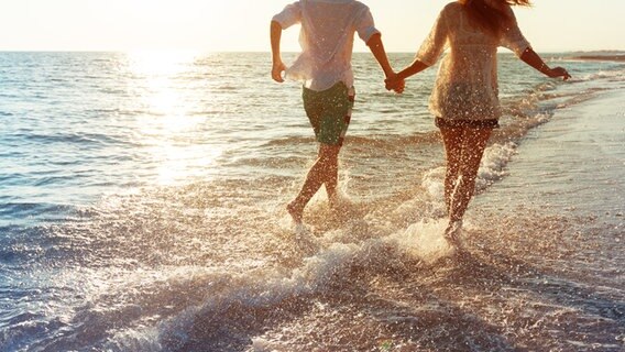Junges Paar läuft bei Sonnenuntergang fröhlich am Meer. © fotolia Foto: fotofabrika