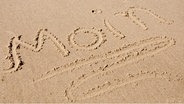 Das Wort moin geschrieben im Sand am Strand © Fotolia.com Foto: O.K.