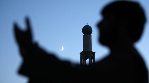 Mann vor Moschee mit Mondsichel im Hintergrund. © EPA 