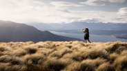 Ein Rucksack-Tourist steht an der Küste und schaut in die Ferne. © maikirmscher / Photocase; Foto: maikirmscher / Photocase;