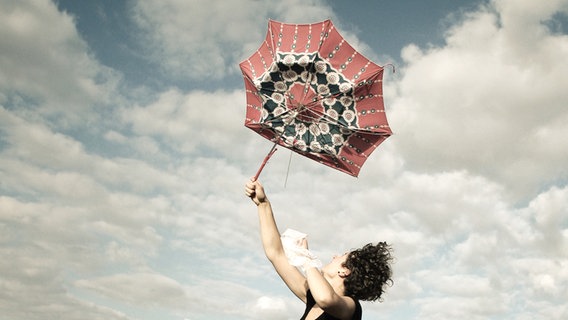 Eine Frau hält einen Regenschirm fest, der wegzufliegen droht. © Jonathan Schöps / photocase.de Foto: Jonathan Schöps / photocase.de