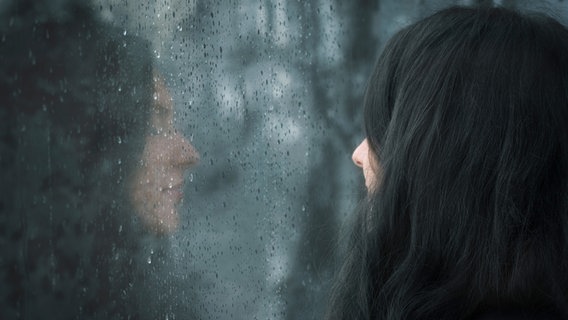 Eine Frau schaut durch ein nasses Fenster. © YesPhotographers / photocase.de Foto: YesPhotographers