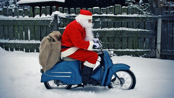 Ein Weihnachtsmann fährt auf einer Vespa durch den Schnee. © photocase Foto: -