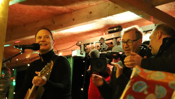 Musiker Fabian Harloff singt gemeinsam mit Landwirten auf einer Bühne. © NDR Foto: Marina Heller