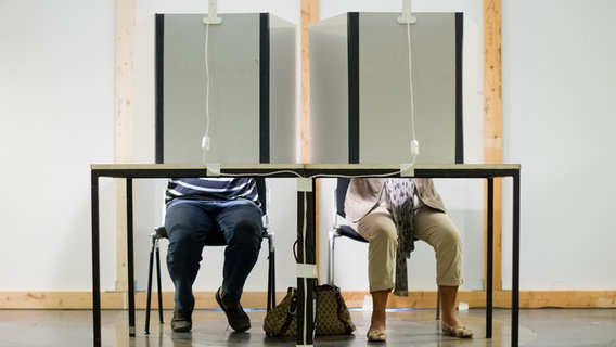 Ein Mann und eine Frau sitzen in einem Wahlraum im Neuen Rathaus in Hannover und füllen ihre Stimmzettel aus. © dpa-Bildfunk Foto: Julian Stratenschulte