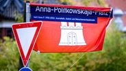 Ein in eine Flagge Hamburgs gehülltes Straßenschild weist auf den Anna-Politkowskaja-Platz hin. © picture alliance/dpa Foto: Axel Heimken