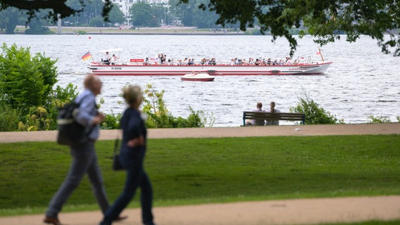 Ausflügler gehen an der Alster spazieren, während ein Alsterdampfer vorüber fährt. © picture alliance/dpa | Jonas Walzberg Foto: Jonas Walzberg