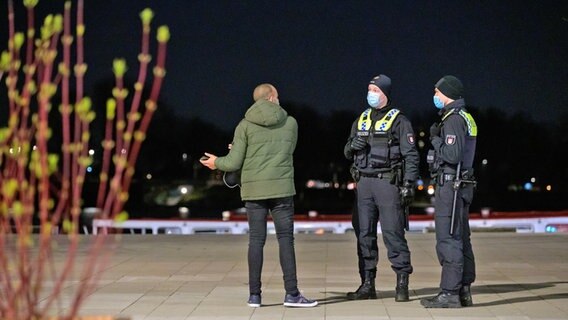 Police officers talk to a man on Jungfernstieg who is outside despite the exit restrictions that have already begun.  © picture alliance / dpa Photo: Jonas Walzberg