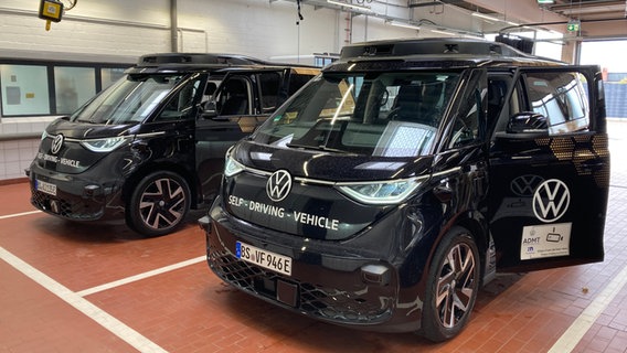 Zwei schwarze VW-Elektrobusse, die in Hamburg als fahrerlose Fahrzeuge gestestet werden, stehen nebeneinander. © NDR Foto: Reinhard Postelt