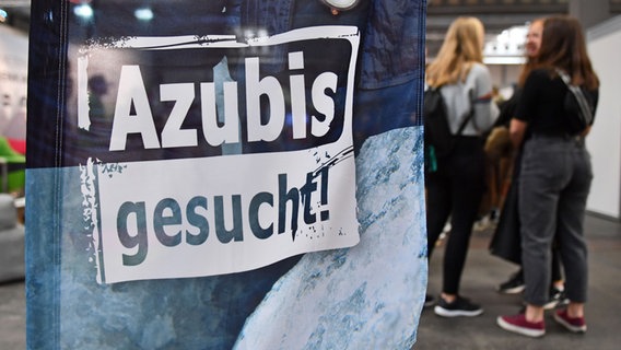 "Azubis gesucht" steht auf einem Banner bei einer Berufsorientierungsmesse. © picture alliance Foto: Martin Schutt