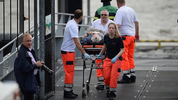Am Hamburger Fischmarkt transportieren Helfer nach einem Barkassenunfall Verletzte ab. © NDR Foto: Christian Wolf