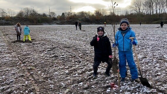 Kinder pflanzen Bäume im Schnee. © NDR Foto: Screenshot