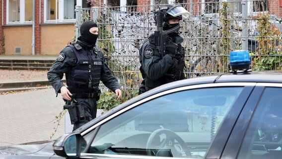 Polizisten gehen bewaffnet vor der Stadtteilschule Blankenese in Hamburg entlang. © dpa Foto: Bodo Marks