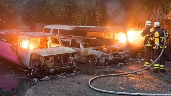 Feuerwehrleute löschen brennende Autos auf dem Gelände eines Autoverleihs in Hamburg-Lohbrügge, darunter mehrere Stretchlimousinen. © dpa Foto: Daniel Bockwoldt