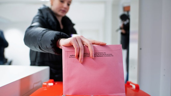 Eine Frau wirft einen Stimmzettel in eine Wahlurne. © picture alliance/dpa Foto: Daniel Reinhardt