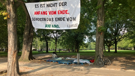 Ein letztes Banner und Paletten bleiben übrig, während das pro-palästinensische Protestcamp gegenüber dem Hamburger Dammtorbahnhof nach vier Monaten abgebaut wird. © picture Alliance / dpa Foto: Thomas Müller