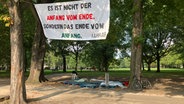 Ein letztes Banner und Paletten sind noch übrig, während das pro-palästinensische Protestcamp gegenüber dem Hamburger Dammtorbahnhof nach vier Monaten abgebaut wird. © picture alliance / dpa Foto: Thomas Müller