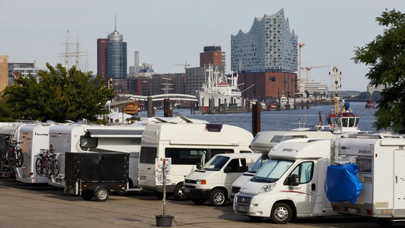 Wohnmobile stehen auf dem einem Parkplatz zwischen Fischmarkt und Landungsbrücken. Im Hintergrund ist die Elbphilharmonie zu sehen. © picture alliance/dpa Foto: Georg Wendt