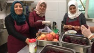 Die Frauen Amina (li.), Fadwa und Maisaa vom Cateringservice "Chickpeace" stehen in einer Küche und entkernen Granatäpfel. © NDR Foto: Susanne Röhse