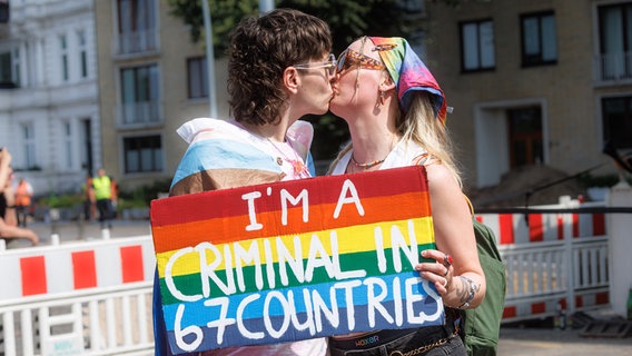 Zwei Frauen halten auf der Demonstration zum Christopher Street Day (CSD) ein Schild mit der Aufschrift "I am a criminal in 67 countries." © picture alliance/dpa Foto: Markus Scholz