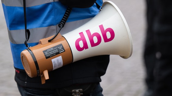 Ein Teilnehmender einer Demo hat ein Handmegaphone umhängen, auf dem der Schriftzug des Beamtenbundes dbb zu sehen ist. © picture alliance/dpa Foto: Robert Michael