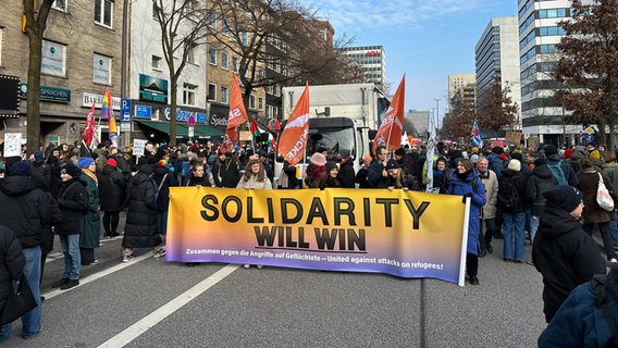 Demonstranten halten bei einer Kundgebung in Hamburg ein Transparent mit der Aufschrift "Solidarity will win". © NDR Foto: Finn Kessler