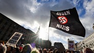 Teilnehmende einer Demonstration in Hamburg halten eine Flagge mit der Aufschrift "Gegen Nazis" hoch. © picture alliance / dpa Foto: Christian Charisius