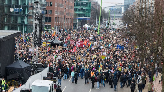 Teilnehmende einer Demo gegen rechts stehen auf der Ludwig-Erhard-Straße in der Hamburger Innenstadt vor einer Bühne. © Georg Wendt/dpa 