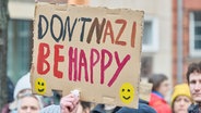 Eine Person hält in Hamburg bei einer Demo gegen einen Rechtsruck in Deutschland  ein Plakat mit der Aufschrift "Don't Nazi Be Happy" in die Luft. © Georg Wendt/dpa 