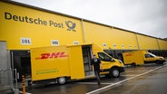 Ein Mitarbeiter gehtzu einem elektrischen Zustellfahrzeug auf der neuen DHL-Zustellbasis in Hamburg-Schnelsen. © picture alliance/dpa Foto: Christian Charisius